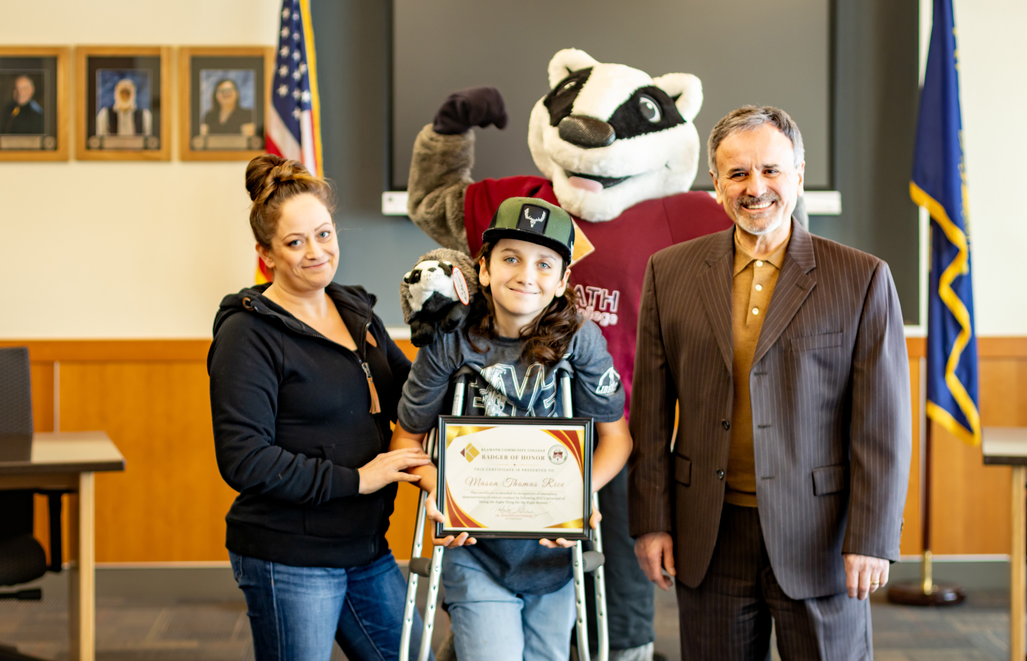 Mason Rice (middle) is joined by his mother Stacy McCarl (left), Baxter the Badger (behind), and Klamath Community College President Dr. Roberto Gutierrez after receiving the Badger of Honor award for upstanding citizenship